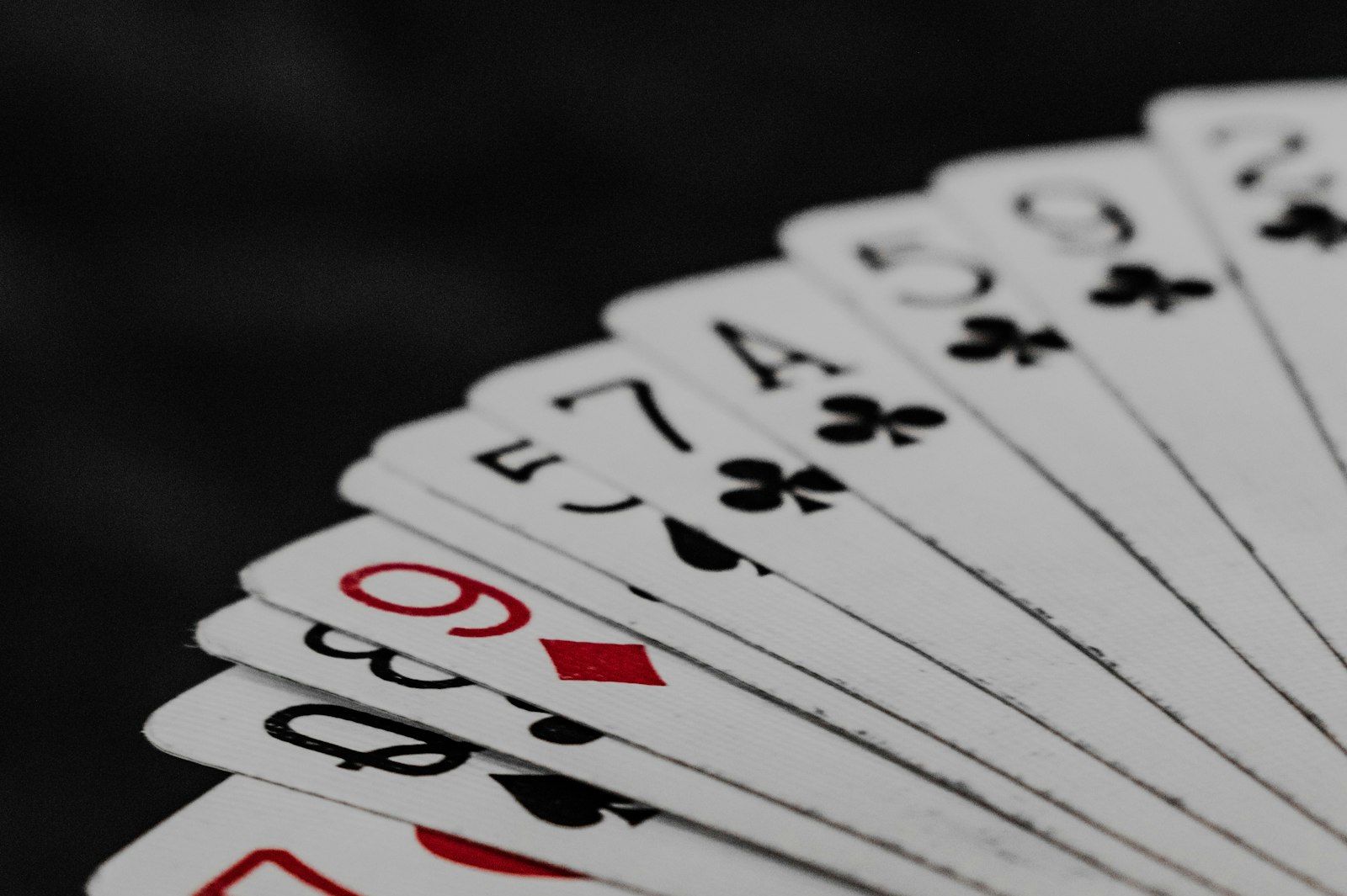 A deck of playing cards fanned out on a dark background A deck of playing cards fanned out on a dark background