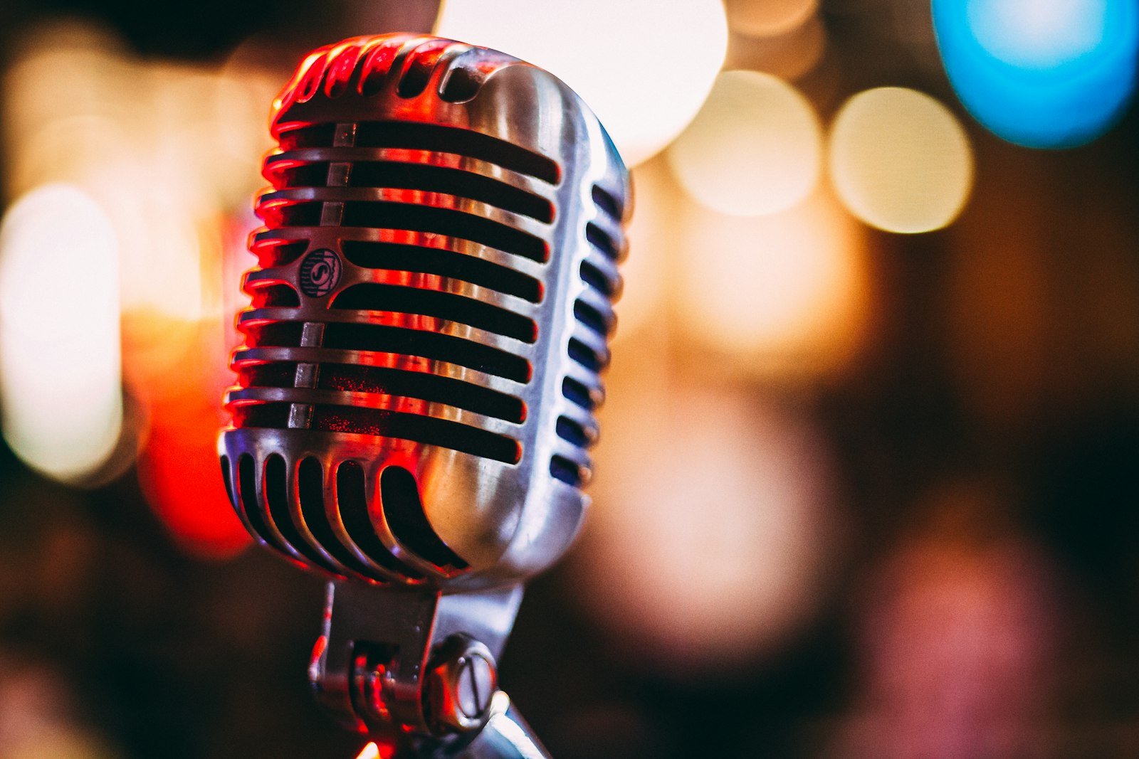 A vintage microphone in front of blurred stage lights A vintage microphone in front of blurred stage lights